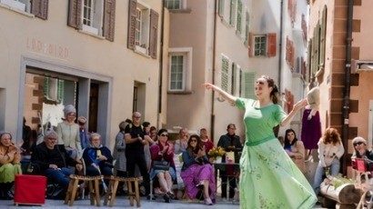 Tänzerin in grünem Kleid vor Publikum auf einem Platz