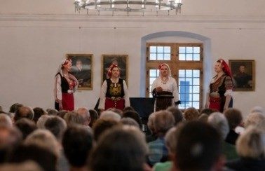 Frauen in Trachten singen vor Publikum in einem Saal